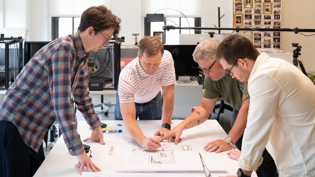 CFB engineers collaborating over subdivision grading plans at a drafting table.